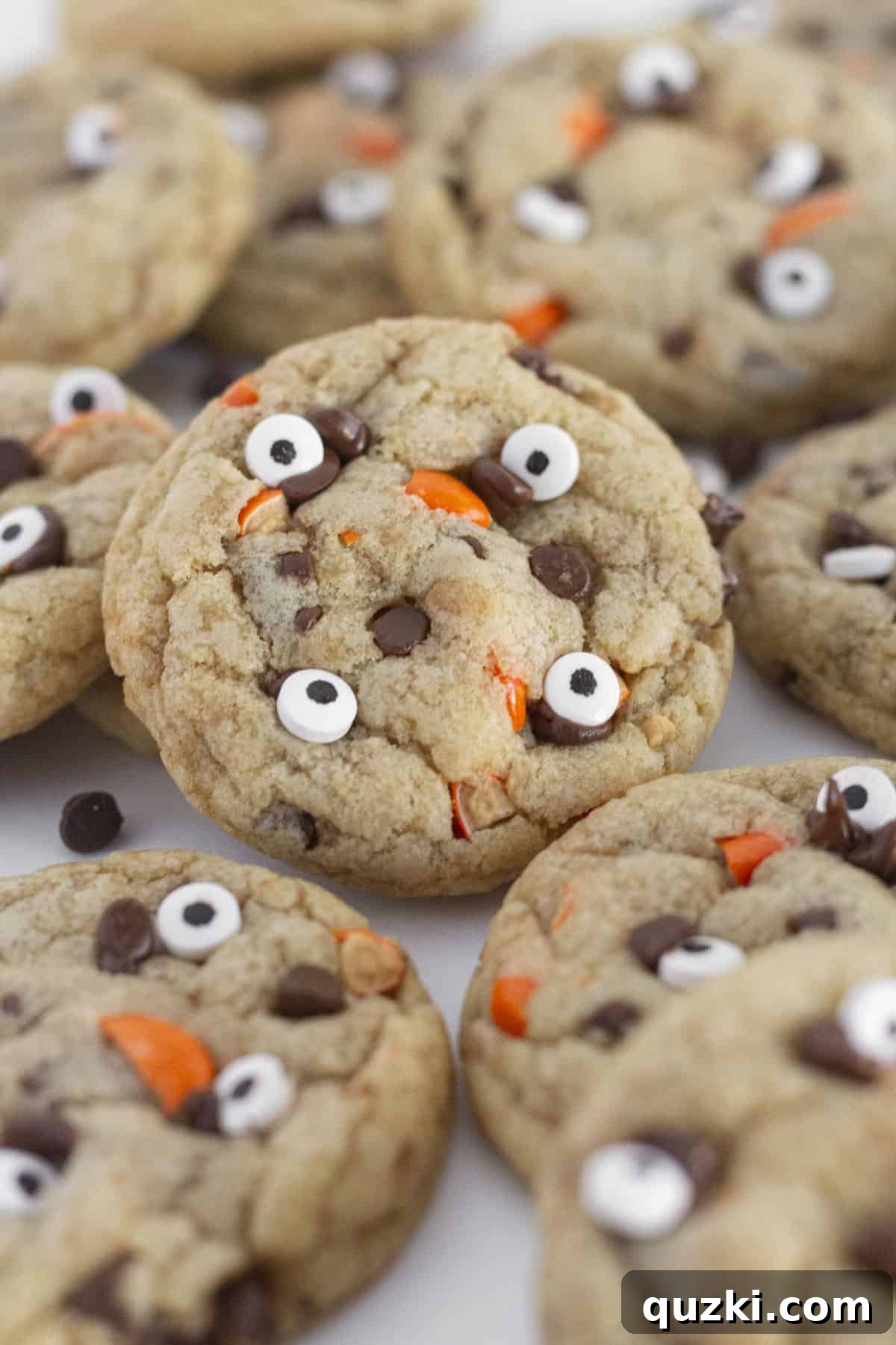 Easy Halloween Chocolate Chip Cookies featuring orange candies and edible eyeballs, ready to eat on a white plate, perfect for a spooky treat.