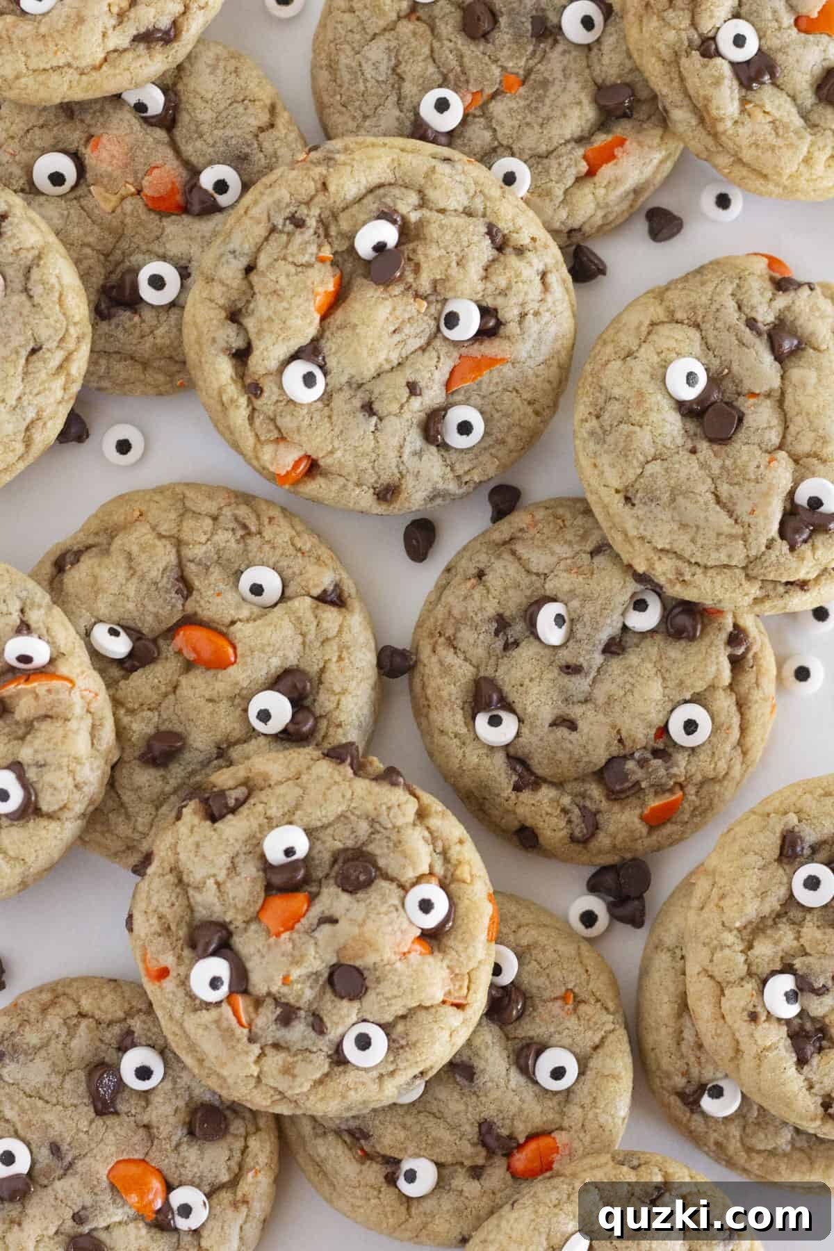 A baking tray filled with freshly baked Halloween Chocolate Chip Cookies, each adorned with orange candies and edible googly eyes.