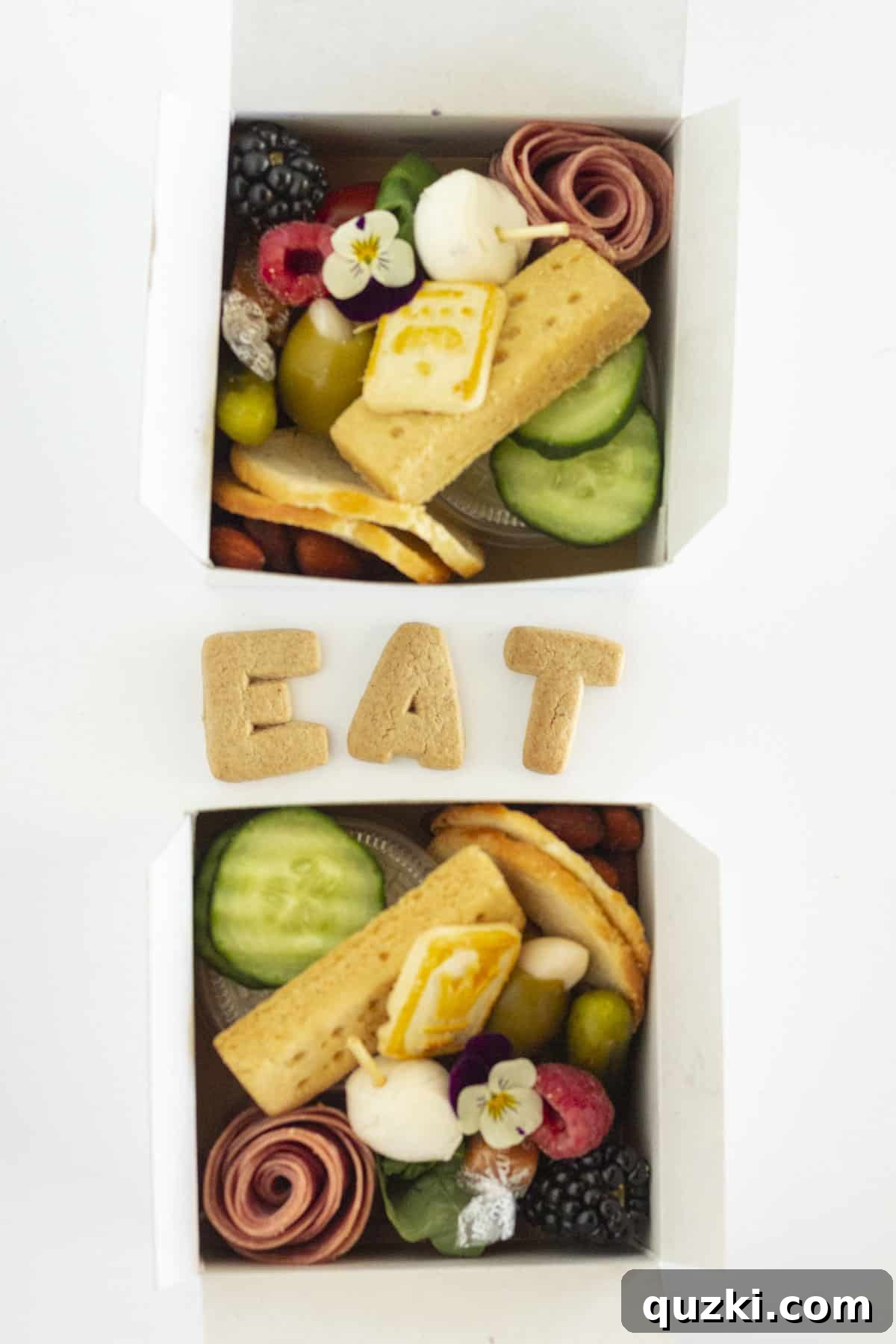Two finished individual charcuterie boxes, elegantly packed with a variety of gourmet items including meats, cheeses, fruits, and crackers.