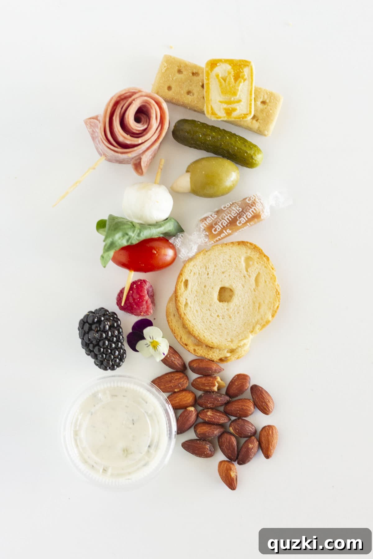 An organized layout of all the ingredients required for assembling a single serving charcuterie box.