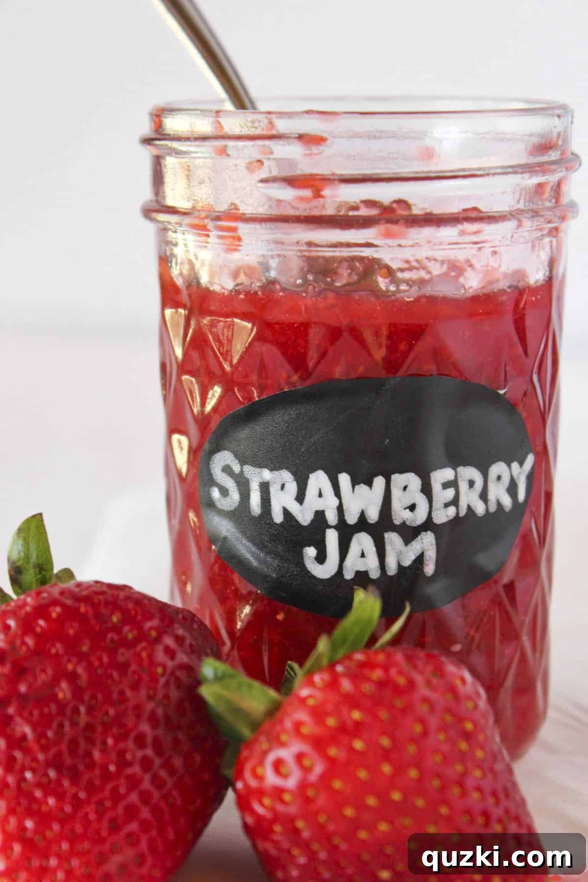 Simple Pectin-Free Homemade Strawberry Jam 2 A jar of homemade strawberry jam with a spoon in the jar and fresh strawberries.
