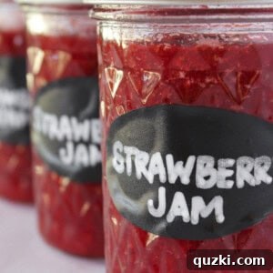 Three jars of strawberry jam with lids and labels.