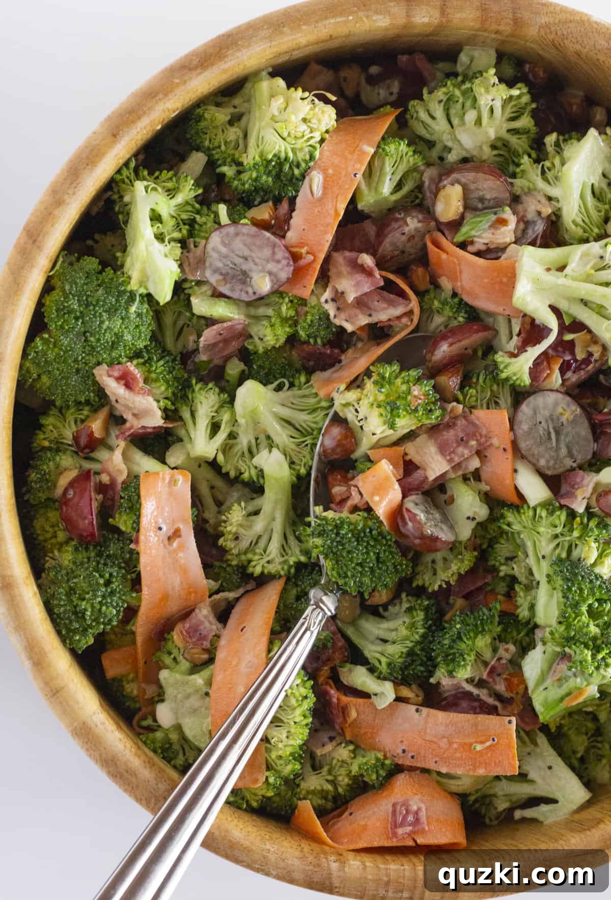 Smoky Bacon Broccoli Crunch Salad 2 A beautiful wooden salad bowl filled with the vibrant Broccoli Crunch Salad, showcasing crispy bacon, sweet red grapes, and fresh broccoli florets.