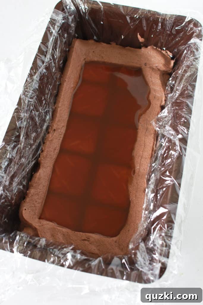 Pouring a generous quarter cup of glistening caramel sauce precisely over the shortbread cookie layer, nestled within its protective chocolate pudding ring, for the Twix Icebox Cake.