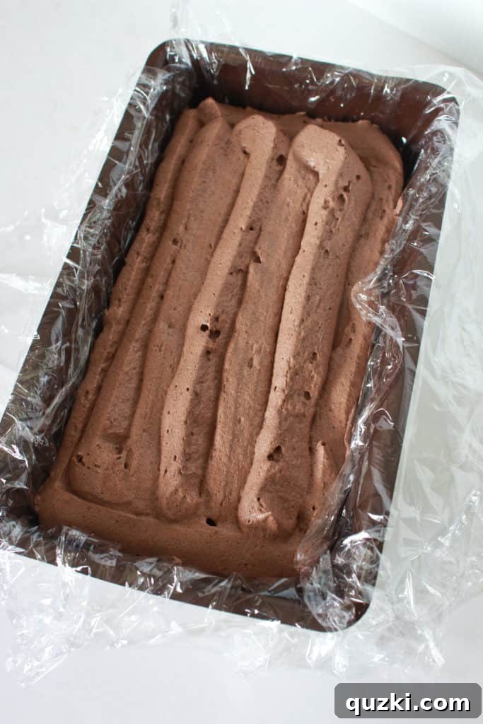 The final set of layers completed in the loaf pan, showing the rich chocolate, shortbread, and caramel, ready for the Twix Icebox Cake to be securely wrapped and chilled.