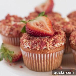 Strawberry crunch cupcakes on a white cake plate with fresh strawberries.