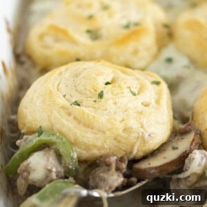 Serving a spoonful of Philly Cheesesteak casserole with crescent roll top.