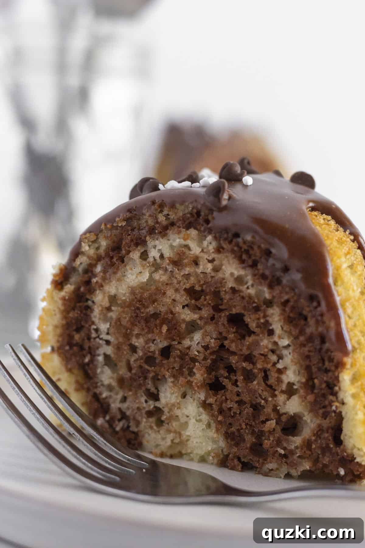 Velvety Chocolate Vanilla Swirl Bundt Cake 8 A perfectly portioned slice of marble bundt cake on a white plate with a fork, ready to be enjoyed.
