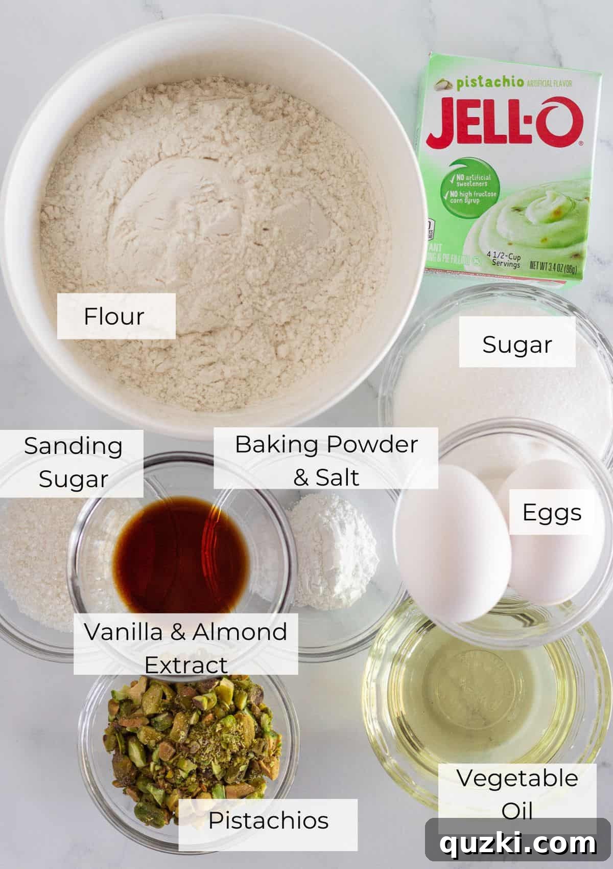 Pudding Mix Perfection: Effortless Pistachio Muffins 3 A flat lay photograph showcasing all the individual ingredients required to make pistachio muffins, including instant pistachio pudding mix, flour, sugar, eggs, milk, oil, extracts, and shelled pistachios.