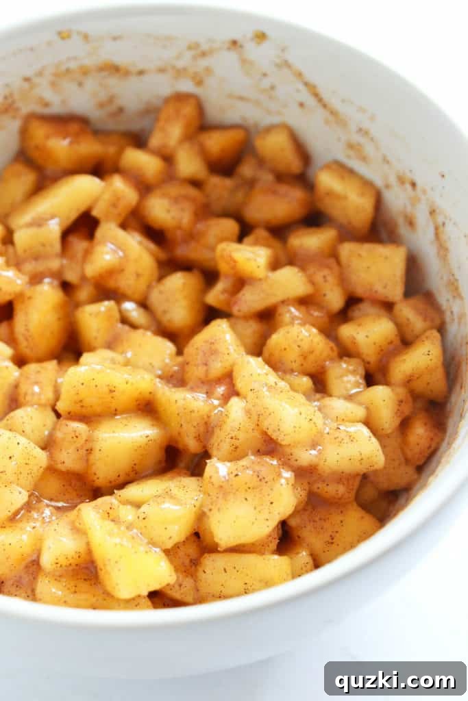 Close-up of freshly diced peaches mixed with brown sugar, cinnamon, and cornstarch in a glass bowl, showcasing the vibrant filling ingredients.