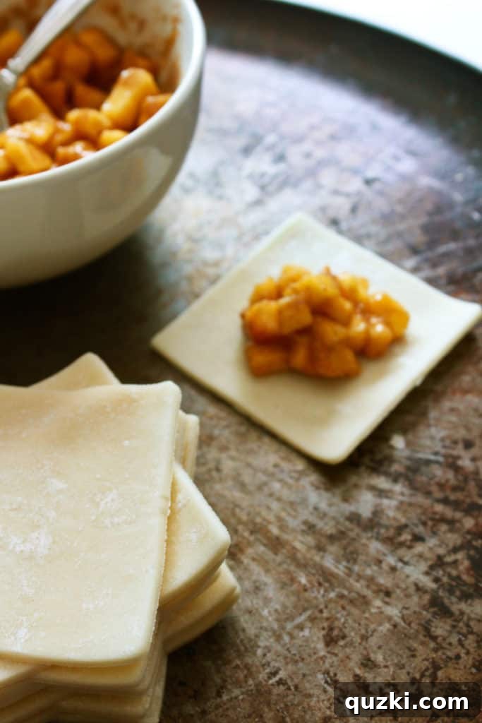 A small, measured mound of peach filling carefully placed in the exact center of a square of pie dough, illustrating the 'do not overfill' principle.
