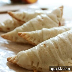 A close-up of a single fresh peach turnover, showcasing the golden crust and sweet glaze, highlighting its deliciousness.
