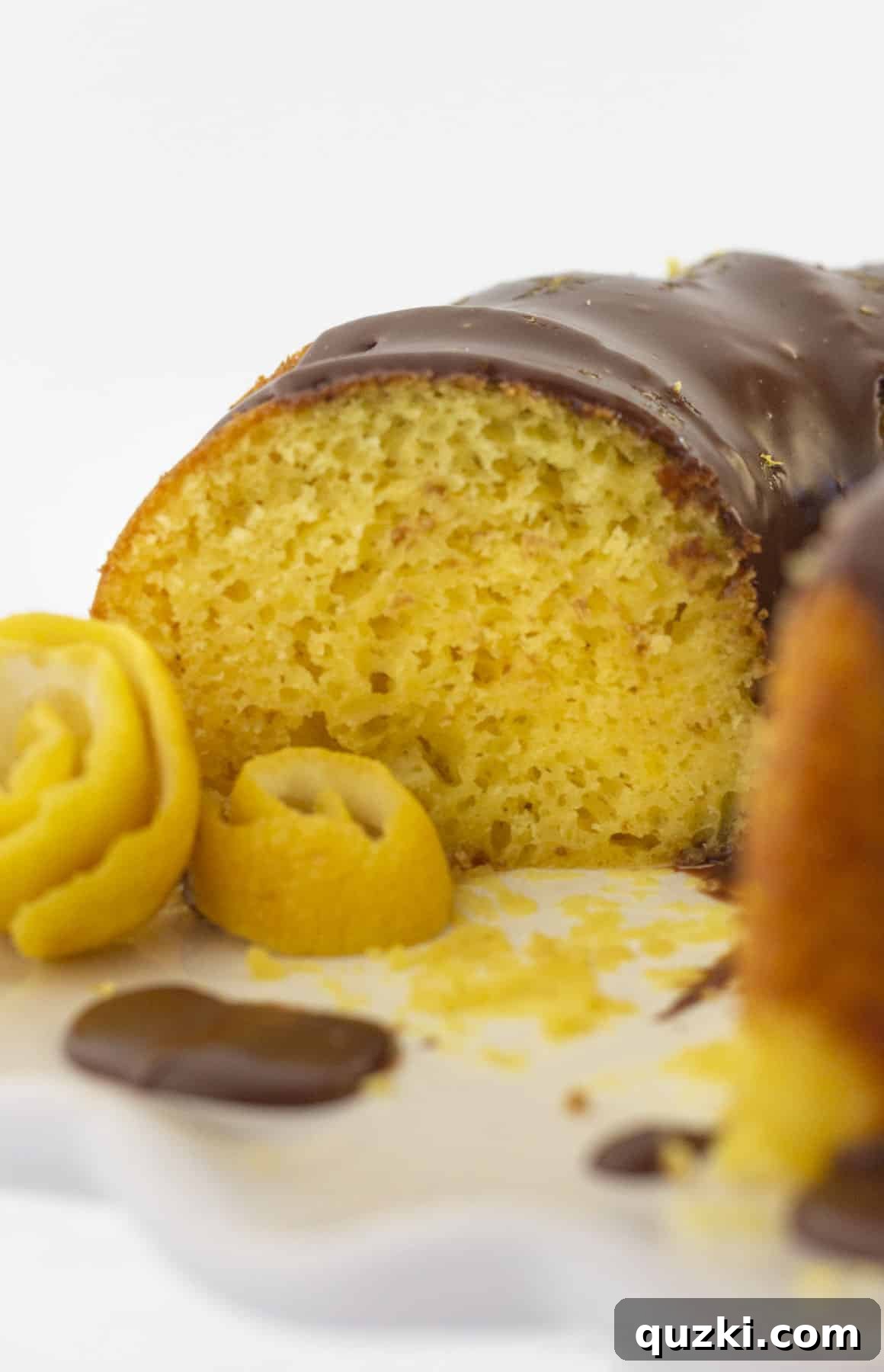 Ultimate Chocolate Lemon Bundt Cake 2 A close-up view of a slice of moist lemon cake with dark chocolate ganache drizzled over the top, showcasing the contrasting colors and inviting texture.