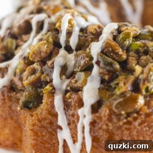 A close up of pistachio bundt cake with vanilla glaze, ready to be served.