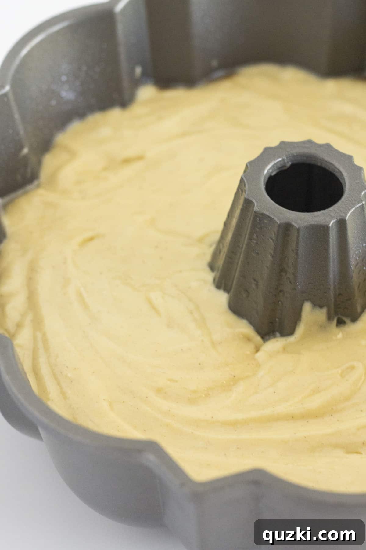 Pound cake batter spread in an even layer in a bundt pan, ready for baking.
