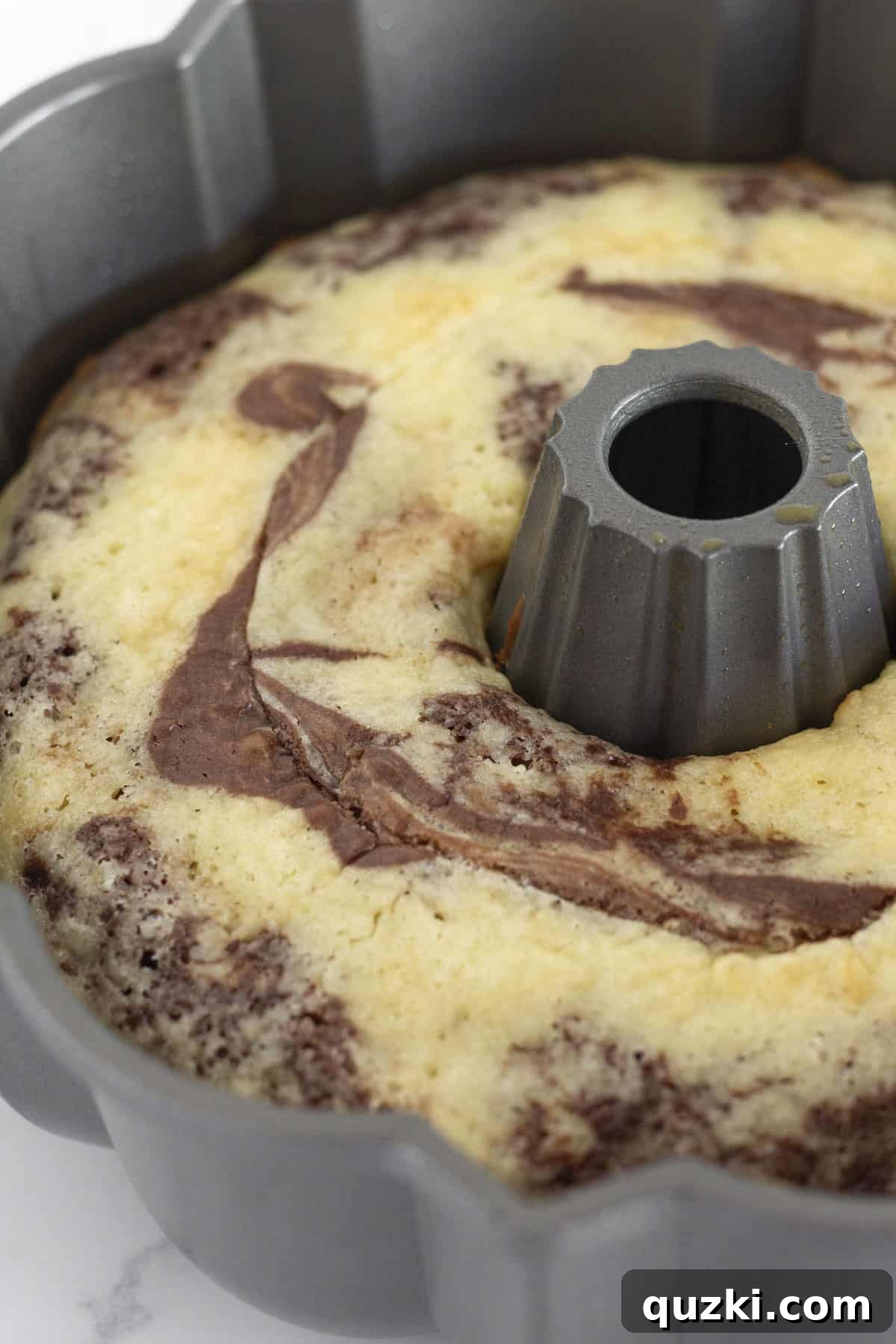 A marble cake in a bundt pan cooling on a rack for 10 minutes.