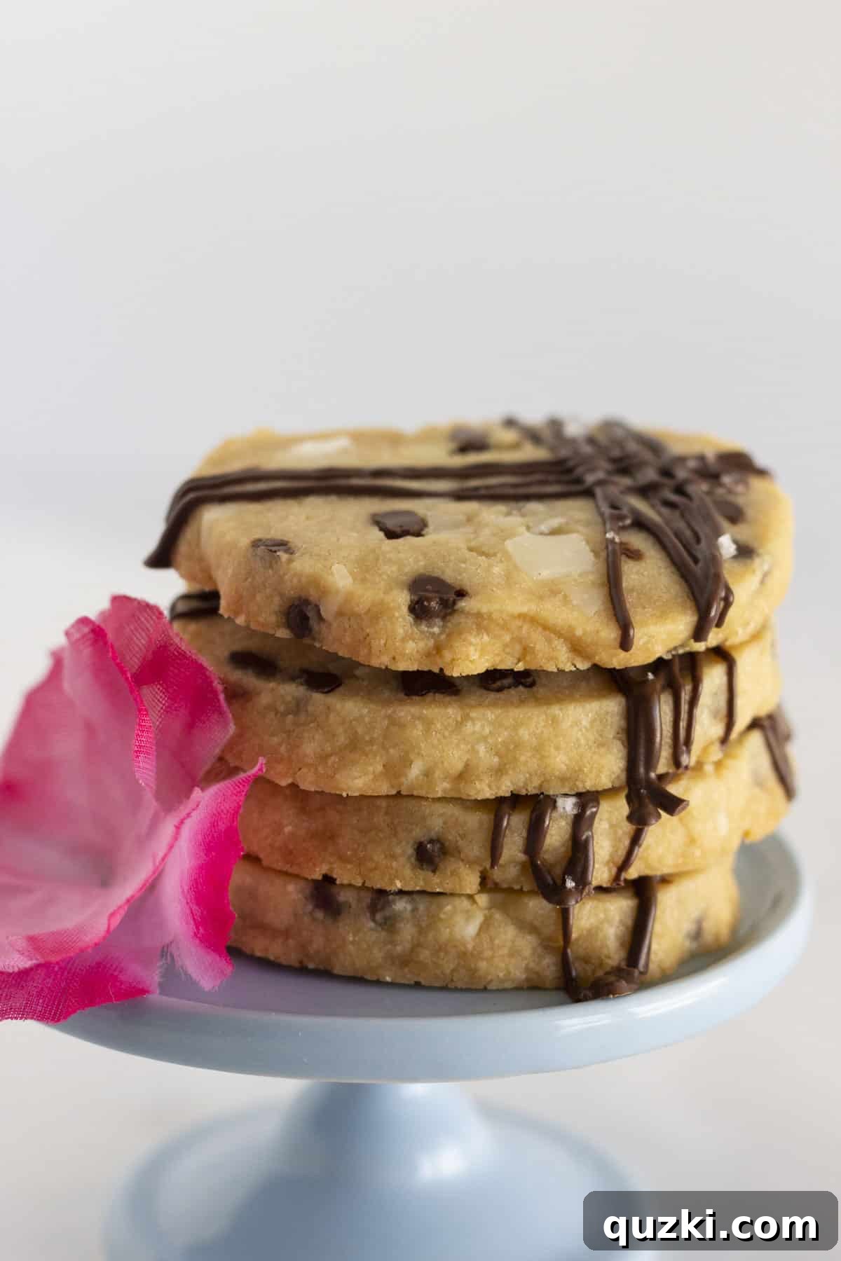Three perfectly baked Hawaiian Shortbread Cookies, drizzled with chocolate and sea salt, elegantly displayed on a blue plate.