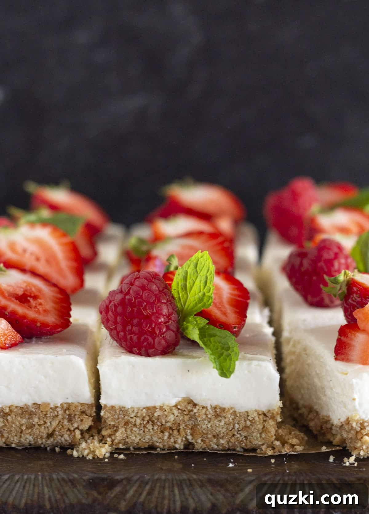 Effortless No-Bake Cheesecake Bars 2 Delicious no-bake cheesecake bars elegantly arranged with fresh, vibrant strawberries as a topping.