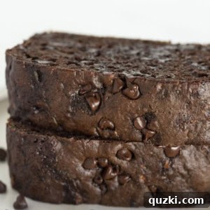 Two slices of chocolate zucchini loaf stacked on a white plate, highlighting its rich, moist texture.
