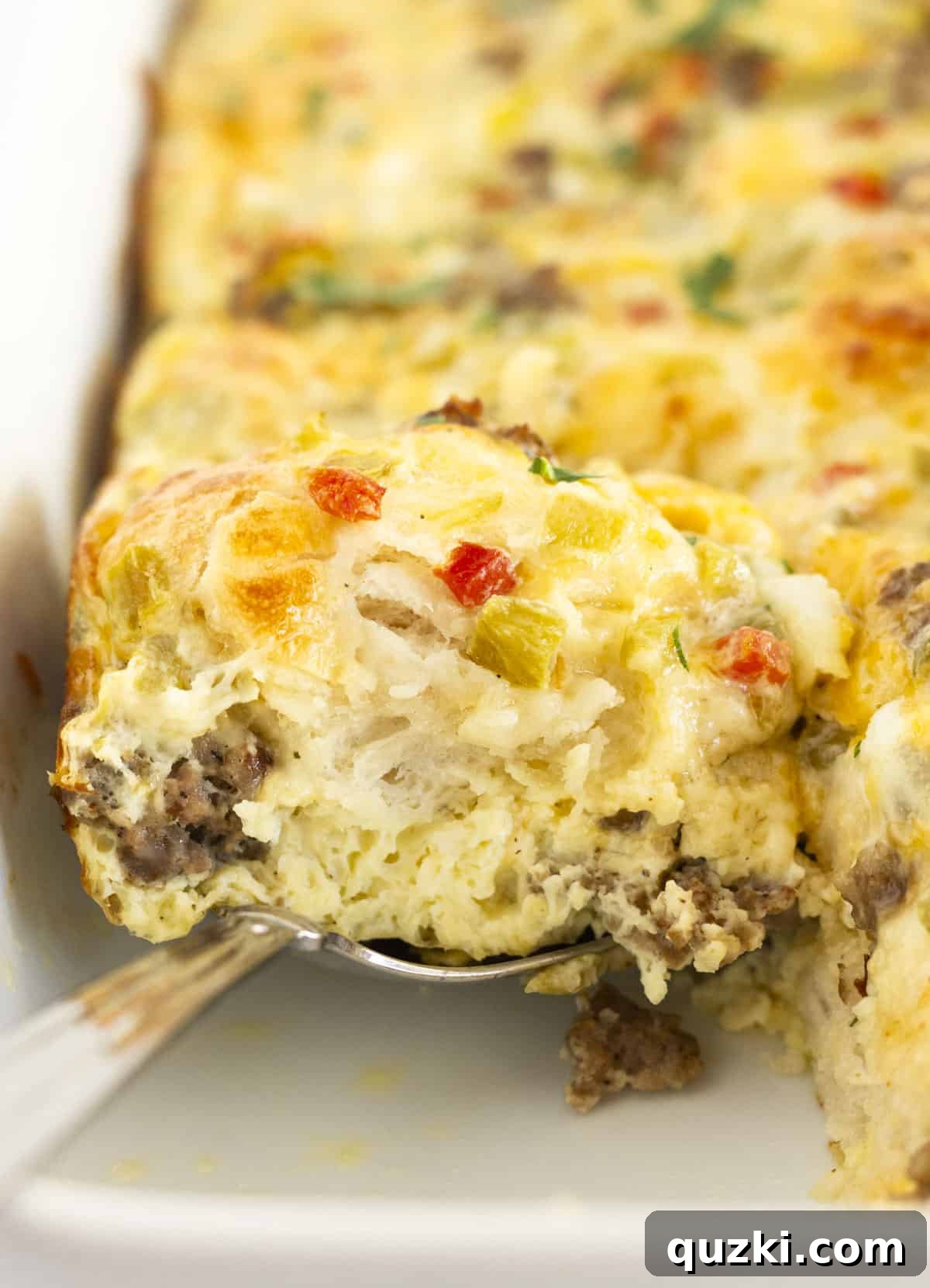 Golden Biscuit Breakfast Bake 2 Serving a square of biscuit casserole with sausage and eggs.