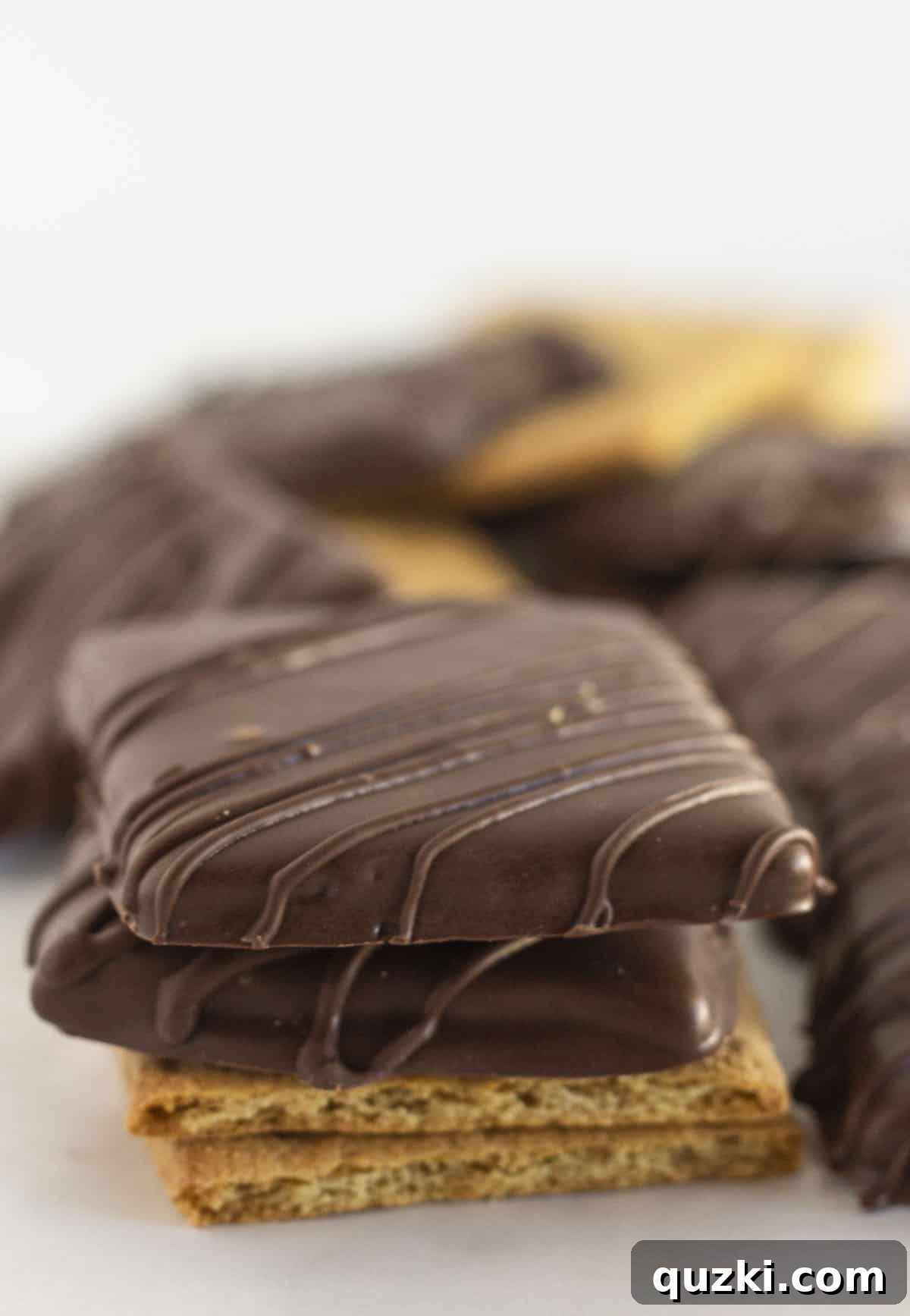 Chocolate covered graham crackers stacked on each other, showcasing their perfect coating and golden-brown edges.
