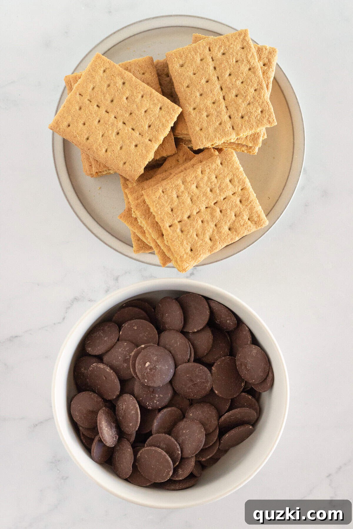 Graham cracker squares and various types of melting chocolate wafers ready for making homemade chocolate covered graham crackers.