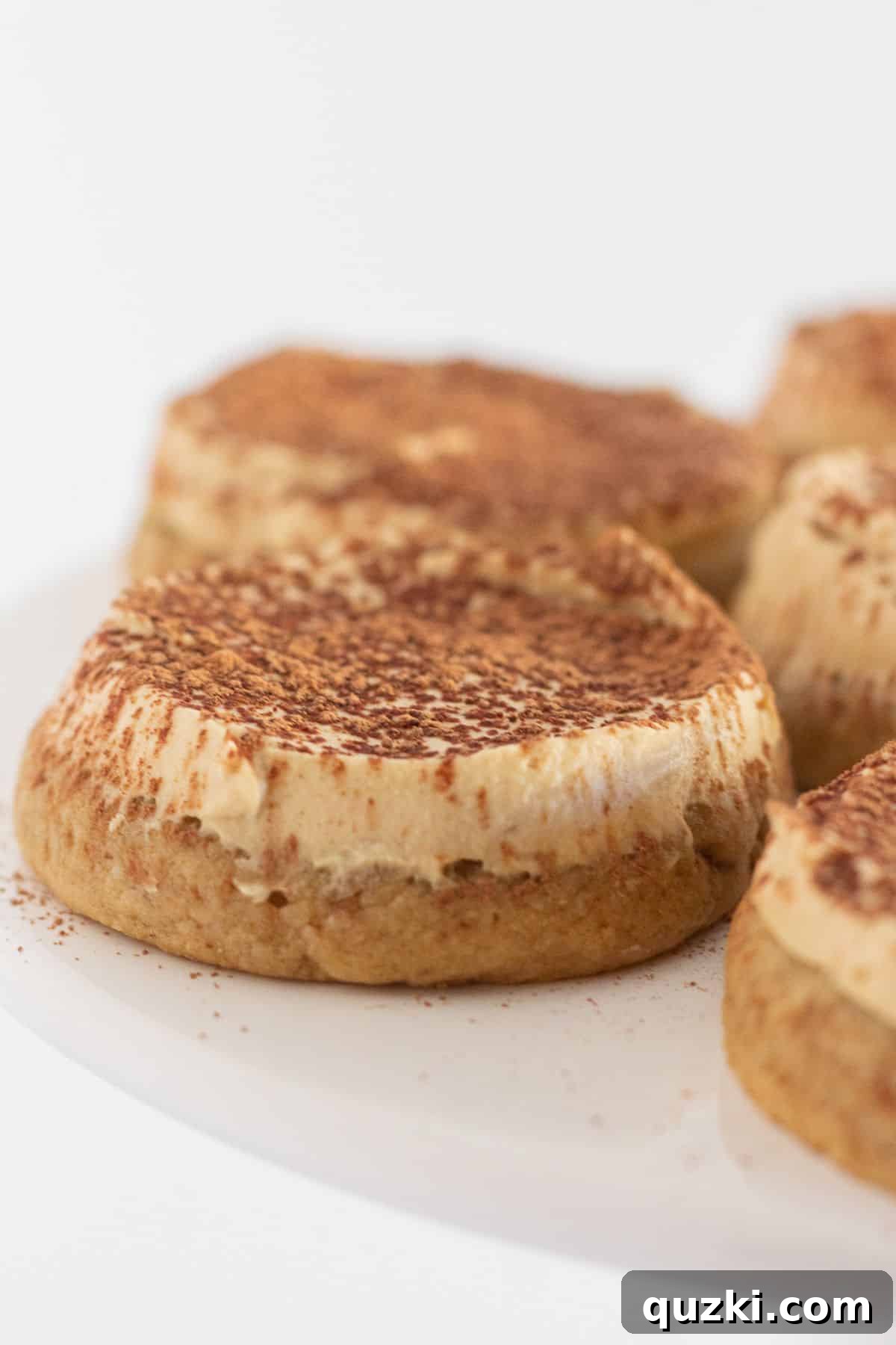 Effortless Tiramisu Cookies 2 Tiramisu cookies perfectly arranged on a white cake plate, showcasing their inviting appearance.
