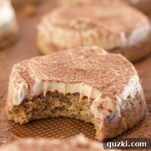 A beautifully frosted Tiramisu cookie on a baking sheet, with a corner gently bitten off to reveal its soft, espresso-infused interior.