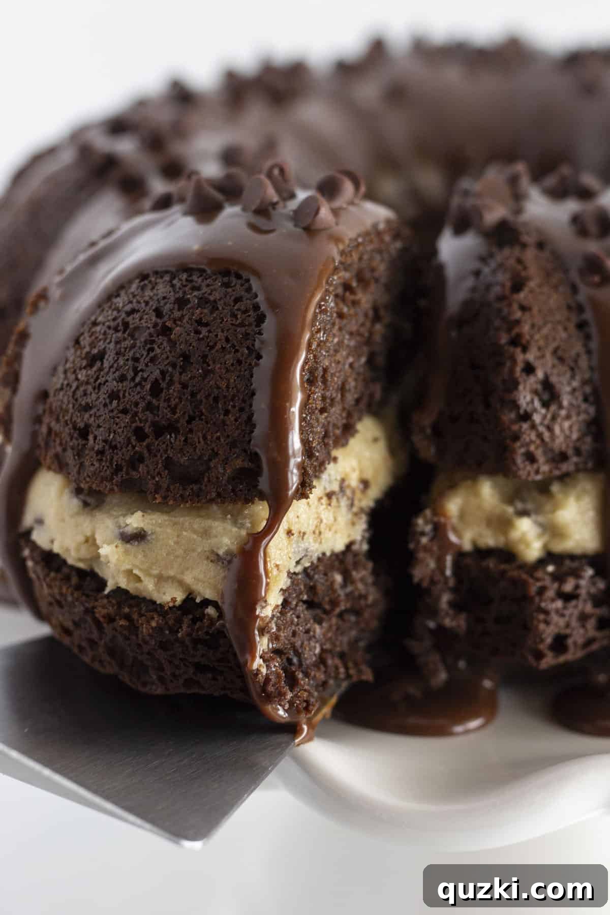 Ultimate Chocolate Chip Cookie Dough Cake 2 Serving a slice of cookie dough cake, revealing layers of chocolate cake and edible cookie dough.