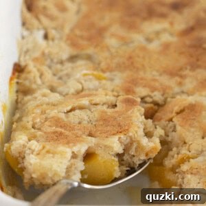 Serving a spoonful of warm peach cake mix cobbler.