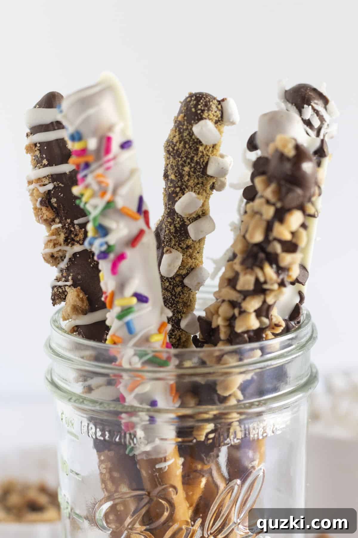 Sweet & Salty Chocolate Pretzel Rods 2 Assorted chocolate covered pretzel rods in a mason jar and on a tray, showcasing various toppings.