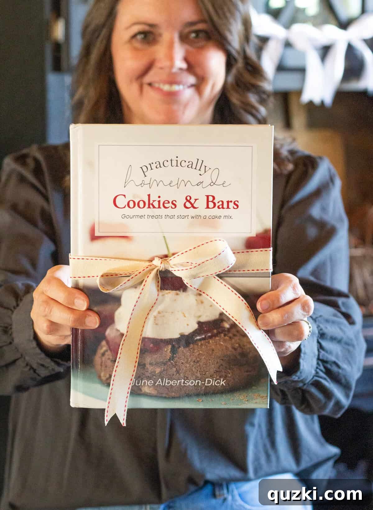 Homemade Cookies & Bars: Simple Recipes 2 June holding a copy of her cookbook with a bow around it, celebrating the launch of Practically Homemade Cookies & Bars.