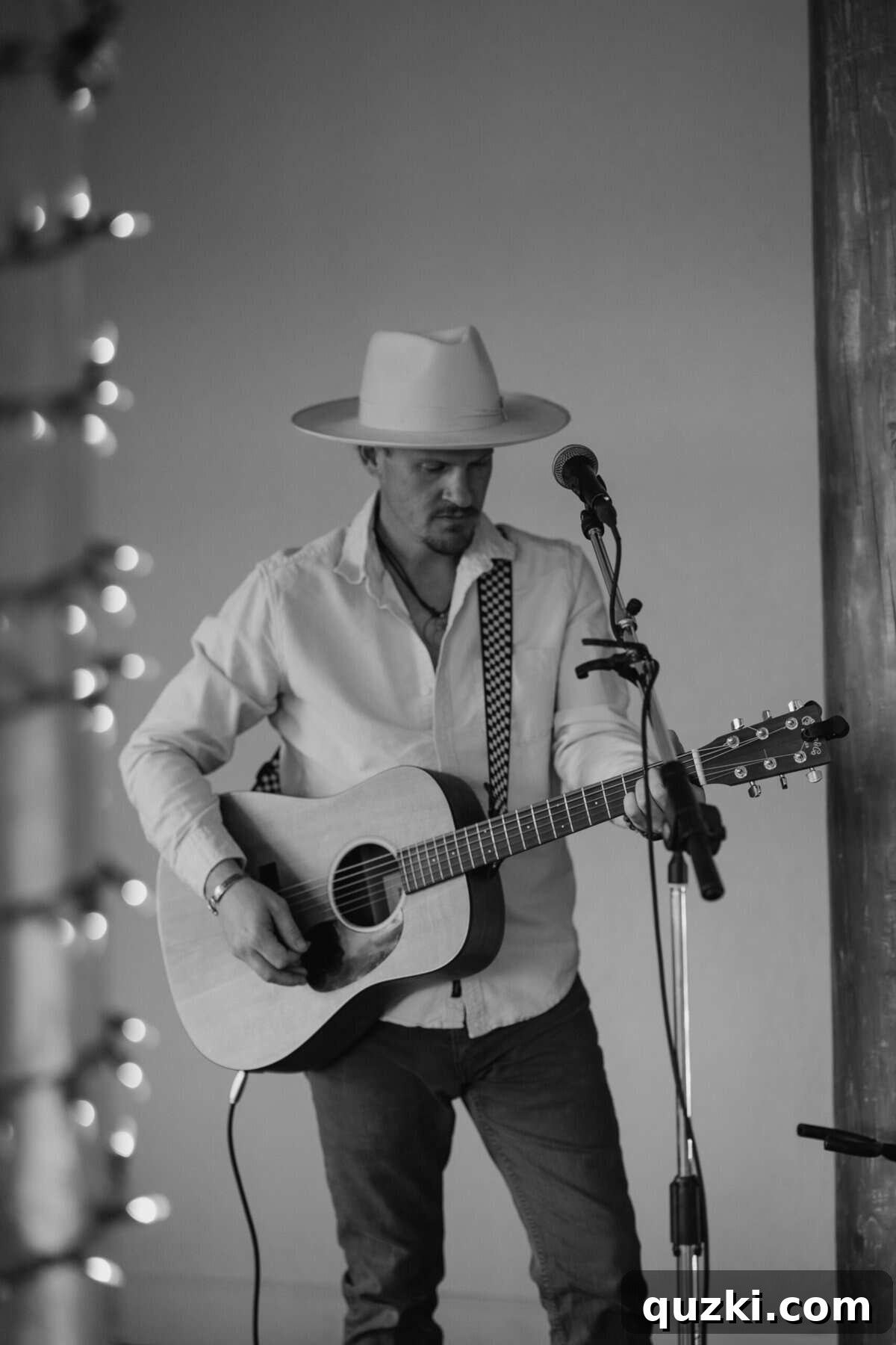 A friend of the couple playing live acoustic guitar and singing during the cocktail hour, providing a warm and engaging musical backdrop for the guests.