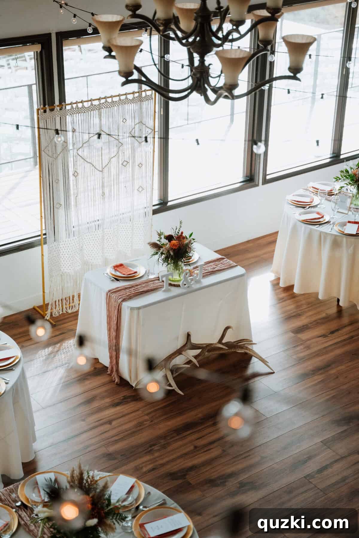 The beautifully decorated sweetheart table for the bride and groom, featuring a macrame backdrop, gold accents, and personal touches like elk antlers.