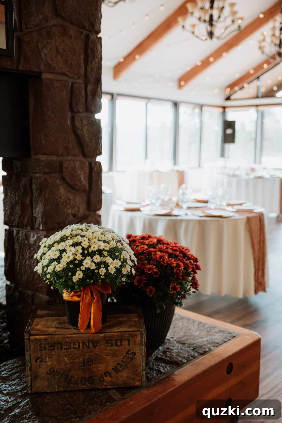 A tastefully arranged corner of the reception, featuring fall-colored mums, burnt orange velvet ribbon, and rustic wooden boxes, enhancing the cozy autumn theme.