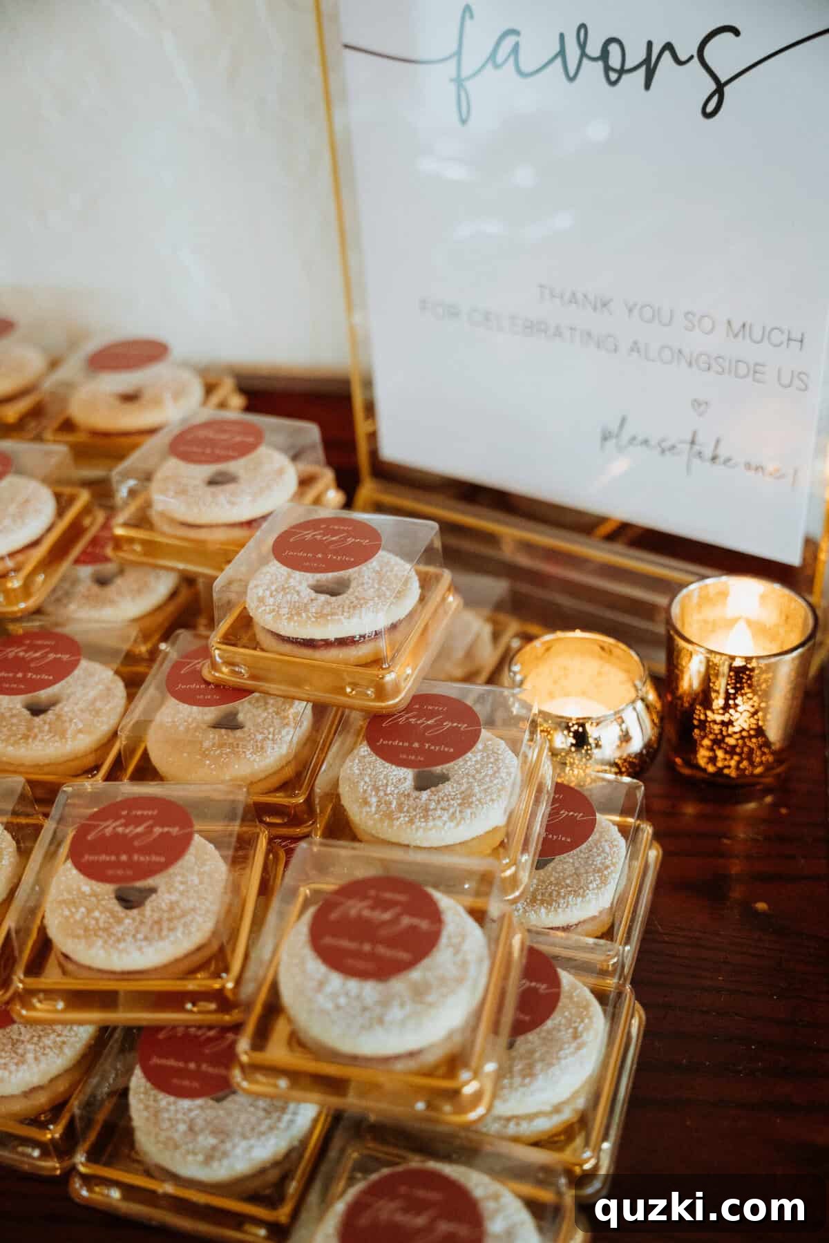 Beautifully packaged homemade sandwich cookies, tied with personalized stickers in gold boxes, ready to be given as wedding favors to guests.