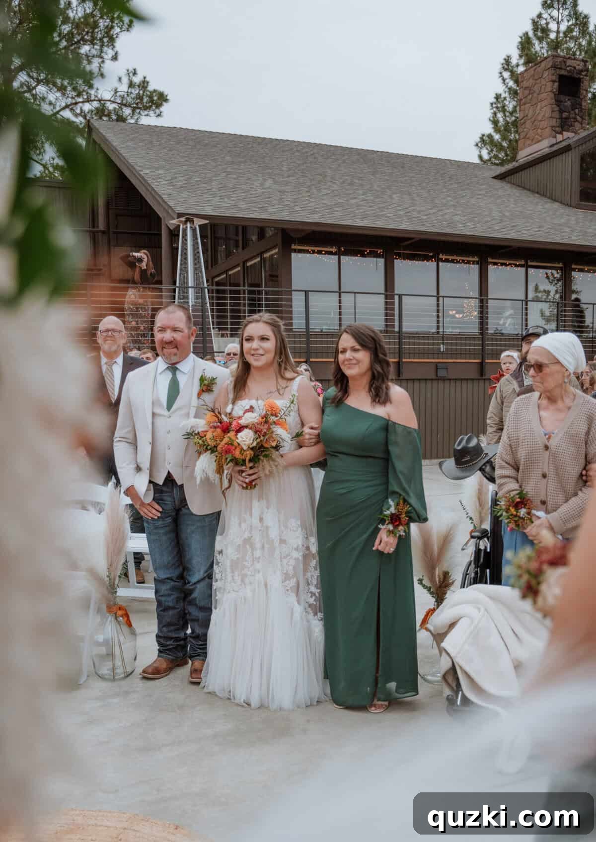 The bride, Taylea, being lovingly escorted down the aisle by both her father and mother, a cherished moment of family unity and pride.