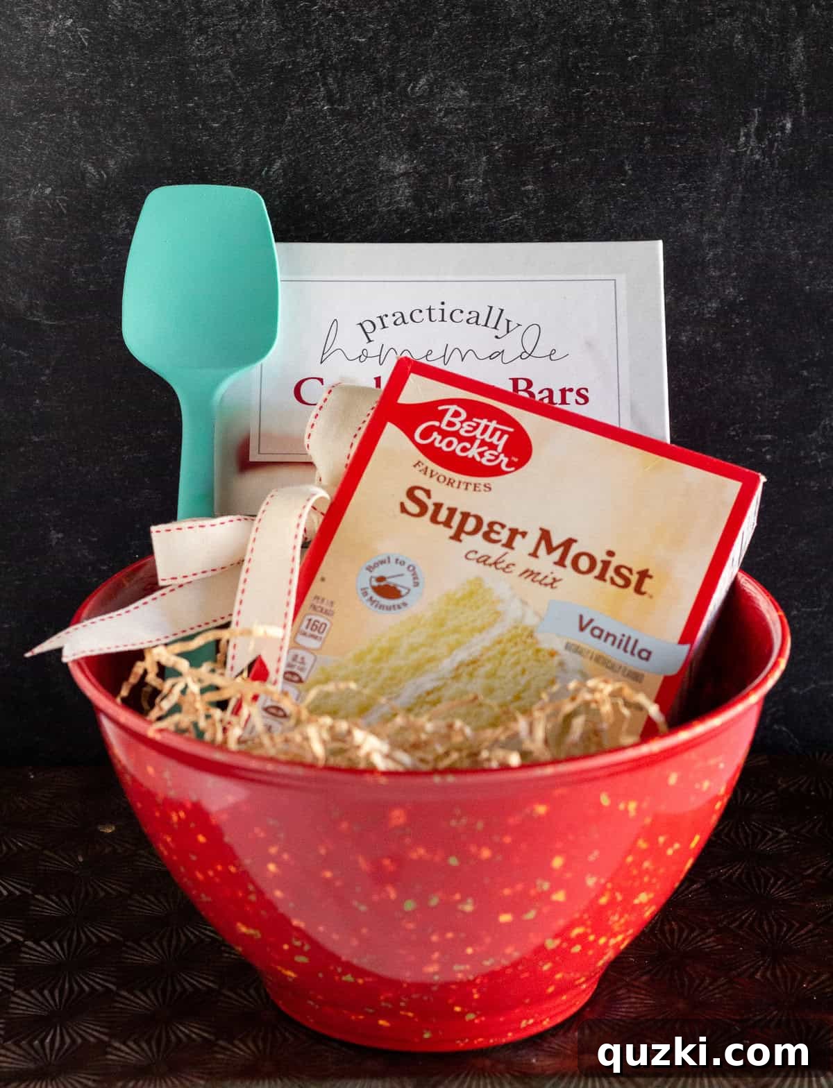 A beautifully presented gift featuring a cookbook, versatile spatula, and a key baking ingredient, all elegantly arranged within a stylish and functional mixing bowl.