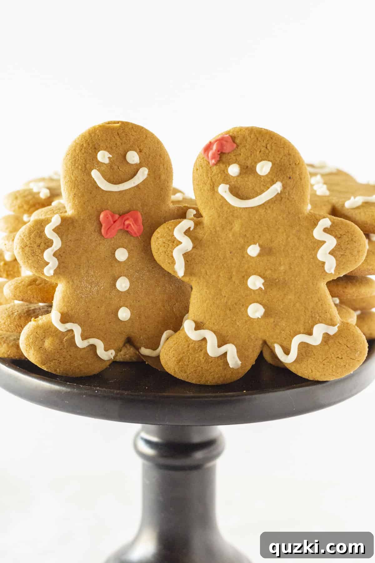 Holiday Cookie Exchange Favorites 5 A charming display of intricately decorated gingerbread cookies on a white cake plate, ready to be enjoyed during the festive season.