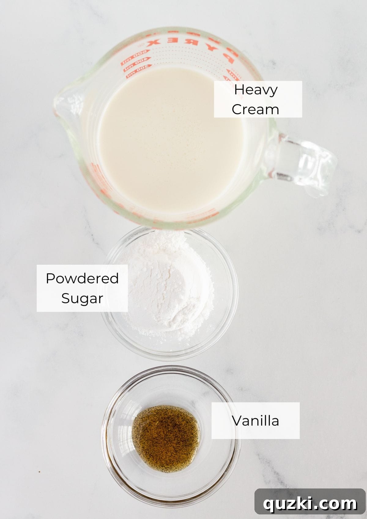 A visual display of the three key ingredients: a carton of heavy whipping cream, a bowl of powdered sugar, and a bottle of vanilla extract, ready for making whipped cream.