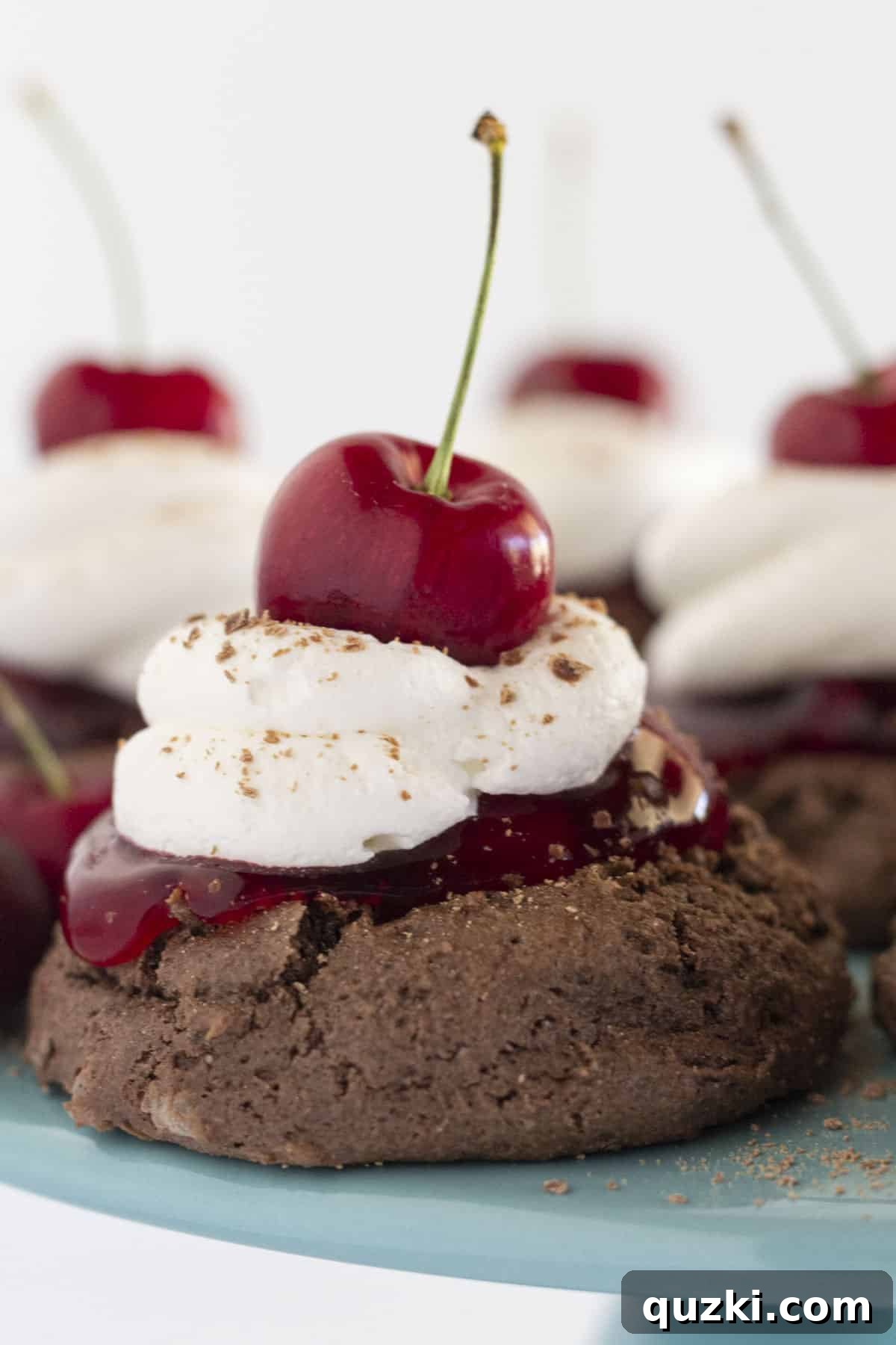 Beautifully piped homemade whipped cream on top of two rich black forest cookies, making a tempting dessert.