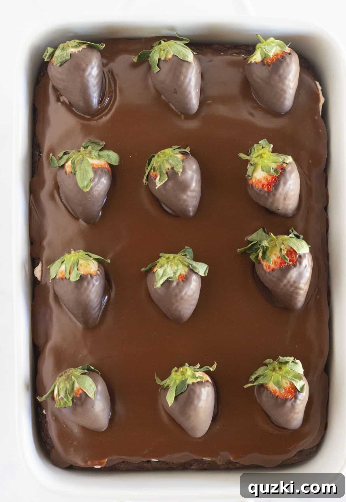 Looking down on a chocolate covered strawberry cake, perfectly garnished and ready to be served.