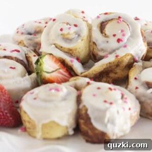 Heart shaped cinnamon rolls on a white cake plate, ready to be served.