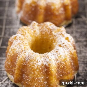 Mini pound cakes cooling on a wire rack, lightly dusted with powdered sugar.