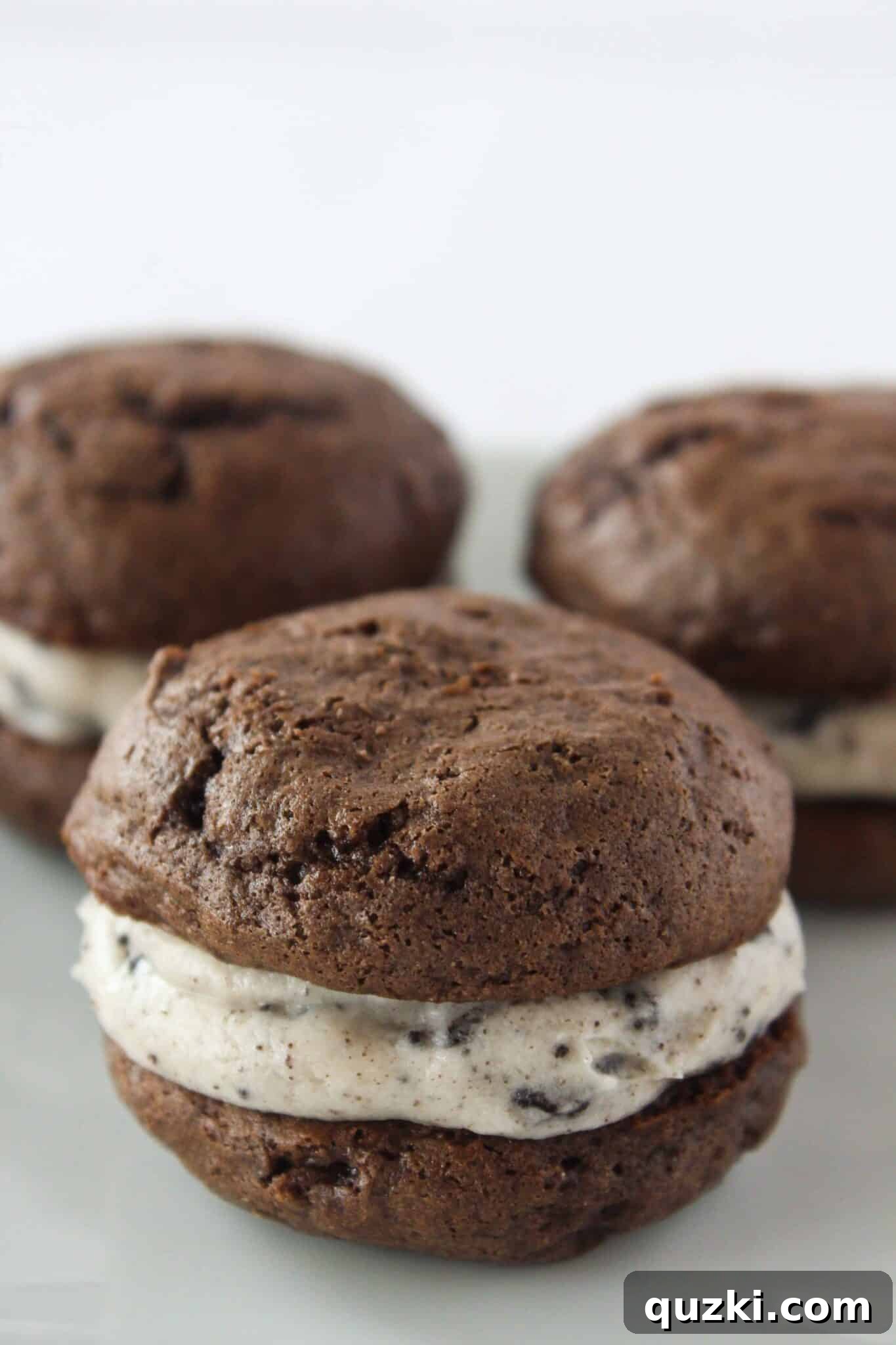 Cake Mix Cookie Magic: Decadent Chocolate Treats 3 Three easy Oreo Whoopie Pies with creamy filling presented beautifully on a white plate.