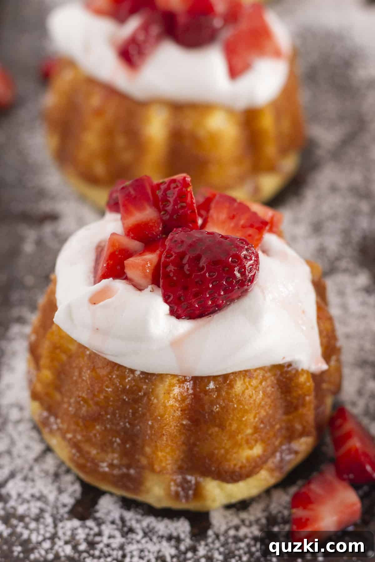 Mini pound cakes elegantly topped with fresh whipped cream and a generous serving of sugared strawberries.