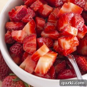 Sugared strawberries in a white bowl with a spoon, ready for serving as a delightful dessert topping.
