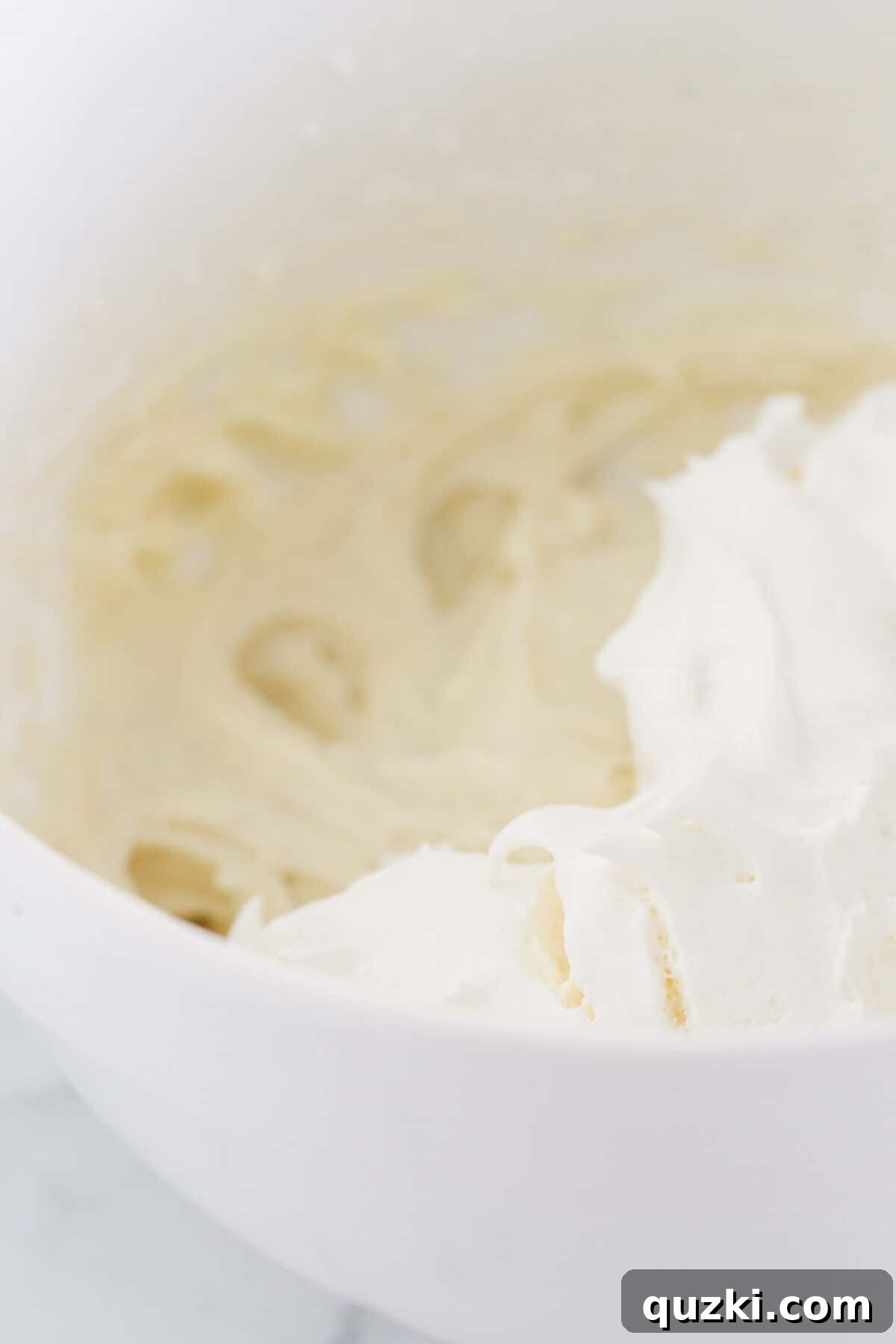 Perfect Vanilla Sheet Cake 7 Making the creamy cheesecake frosting in a white mixing bowl.