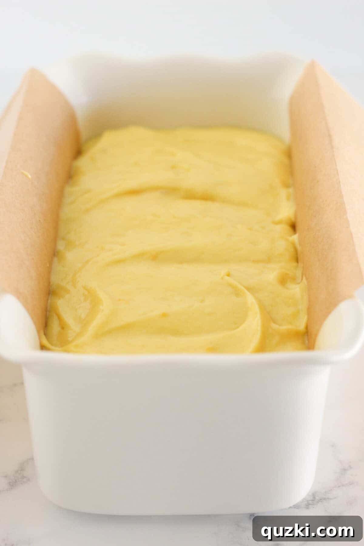 Sunshine Lemon Loaf 5 Smooth lemon loaf batter carefully spread into a white ceramic loaf pan, ready for the oven.