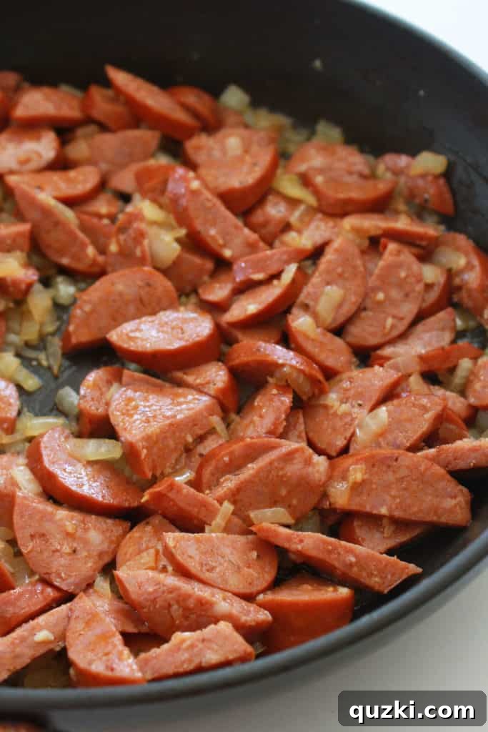 Fast and Flavorful 15-Minute Andouille Sausage Grits 4 Diced onions and minced garlic gently cooking in a pan until translucent, forming the aromatic base for the Andouille sausage dish.